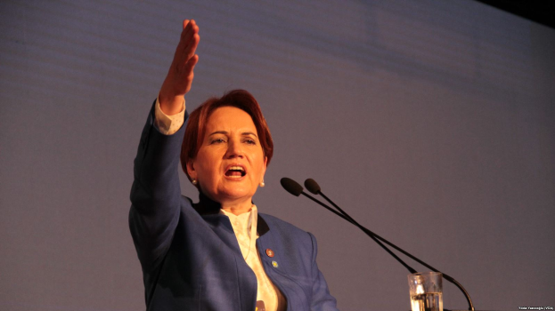 Eine Frau steht an einem Podium mit zwei Mikrofonen und einem Glas Wasser und hält eine Rede vor einem Bildschirm, wahrscheinlich zu einer Regierungsentscheidung, die Frauenrechte zu verbieten.