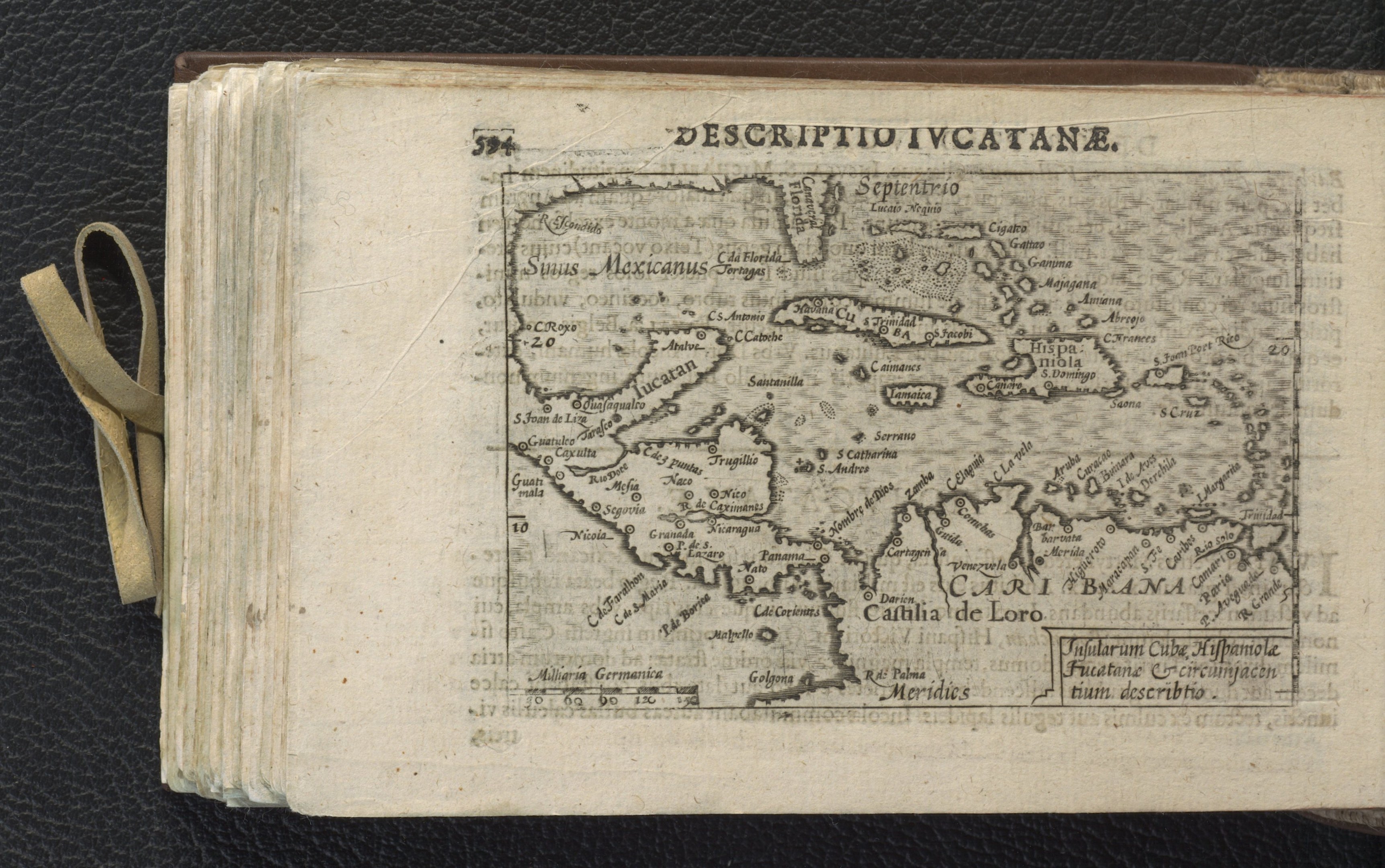 Offenes Buch mit einer detaillierten Karte der Karibik auf einer schwarzen Oberfläche, die Inseln und Gewässer zeigt.