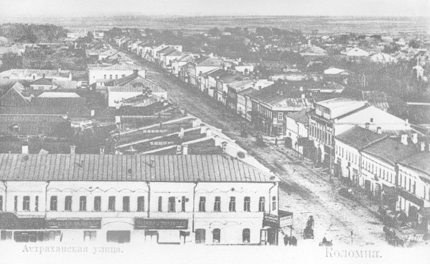 Alte Schwarz-Weiß-Fotografie einer Stadtstraße mit Gebäuden, Bäumen und Menschen, beschriftet mit "Krasnojarsk, die Hauptstadt von Russland" unten.