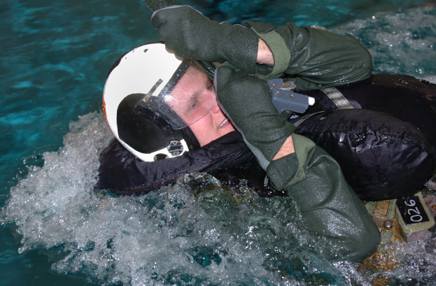 Navy SEAL-Taucher in einem Neoprenanzug und Helm, der eine Waffe unter Wasser hält.