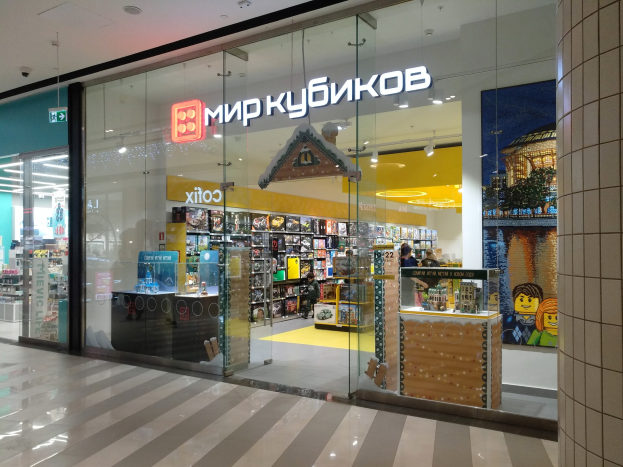 Ladenfront mit einer Glaswand, die das Schild "Миркубиков" in der Mitte zeigt, mit Regalen voller verschiedener Gegenstände darin, eine Säule auf der rechten Seite, befindet sich in Kiew, der Stadtmitte von Ukraine.