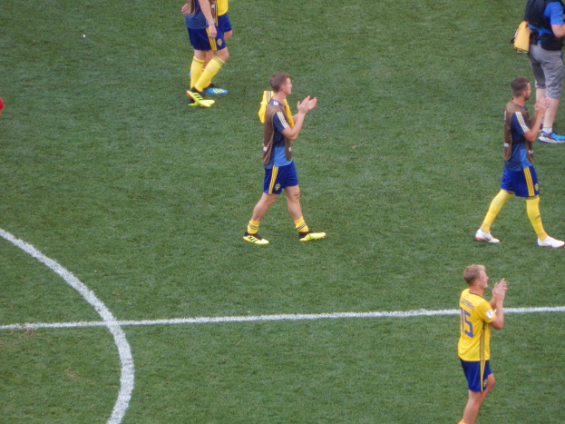 Gruppe von Männern in Fußballtrikots, die auf einem Feld nach einem Spiel klatschen.