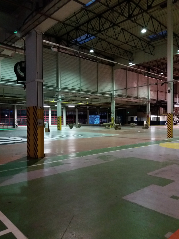 Ein großes Lagerhaus voller verschiedener Maschinen, einschließlich Metallstangen und Lampen, mit Text auf dem Boden auf der rechten Seite.