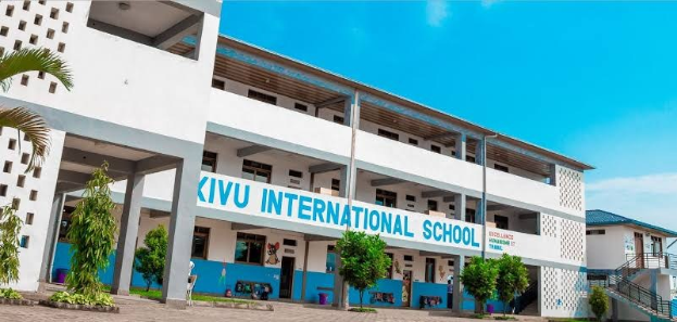 Außenansicht der KIVU International School in Nairobi, Kenia, mit einem mehrstöckigen Gebäude mit Fenstern, Säulen und einem Namensschild, umgeben von Grünflächen und einer Treppe mit Geländern unter einem bewölkten Himmel.