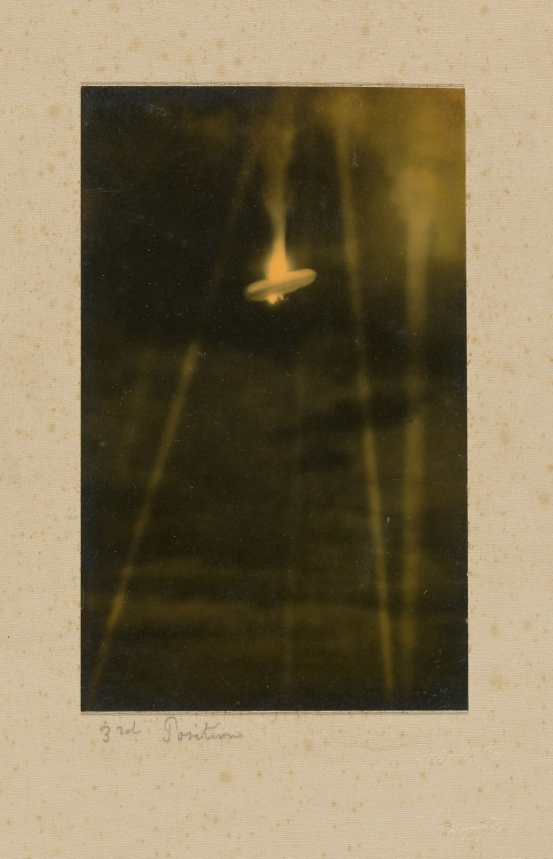 Black and white photo of a UFO flying over a body of water with text at the bottom.