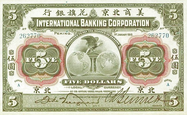 Ein alter Fünf-Dollar-Bankschein der International Banking Corporation, der ein Porträt eines Mannes in Anzug und Krawatte zeigt, mit den Worten "International Banking Corporation" in fetter, schwarzer Schrift darüber, auf einem leicht abgenutzten hellblauen Hintergrund.