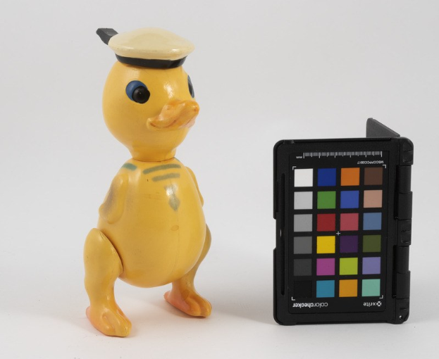 Eine gelbe Gummiente mit einer Matrosenmütze neben einem schwarzen Farbpalette auf einer weißen Oberfläche.