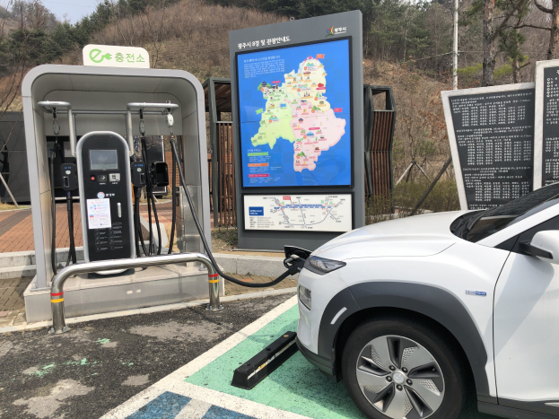 Elektroauto-Laden an einer Station umgeben von Bäumen mit dem Himmel im Hintergrund in Seoul, Südkorea.