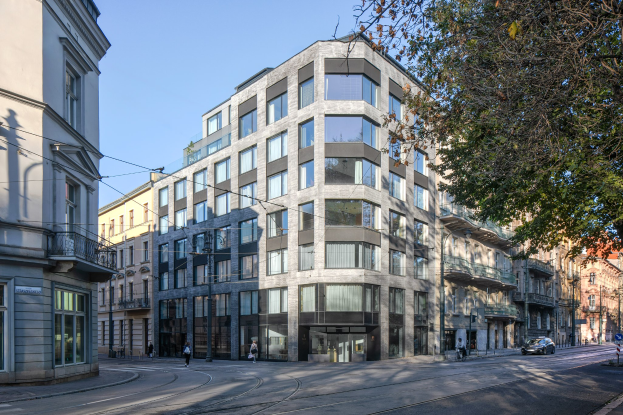 Large office building with many windows, surrounded by street infrastructure, vehicles, pedestrians, trees, and a cloudy sky, identified as a new company headquarters.