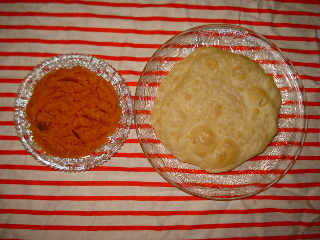 Zwei Schüsseln mit Essen auf einer rot-weißen gestreiften Tischdecke, enthaltend Chapatti, ein traditionelles indisches Fladenbrot aus Mehl, Zucker und Gewürzen.