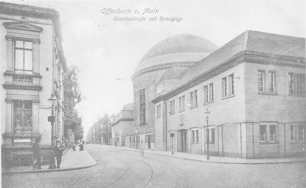 Schwarzes und weißes Foto einer Stadtstraße mit der Beschriftung "Offenbach a. Main, Goethestraße mit Synagoge", das Gebäude, Laternenpfähle, Lampen, Bäume und Fußgänger zeigt.