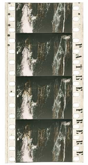 Film strip featuring a black and white waterfall cascading down a rocky cliff, with "ARTIST" in bold text at the top, surrounded by green trees and shrubs under a deep blue sky with a setting sun casting an orange glow.
