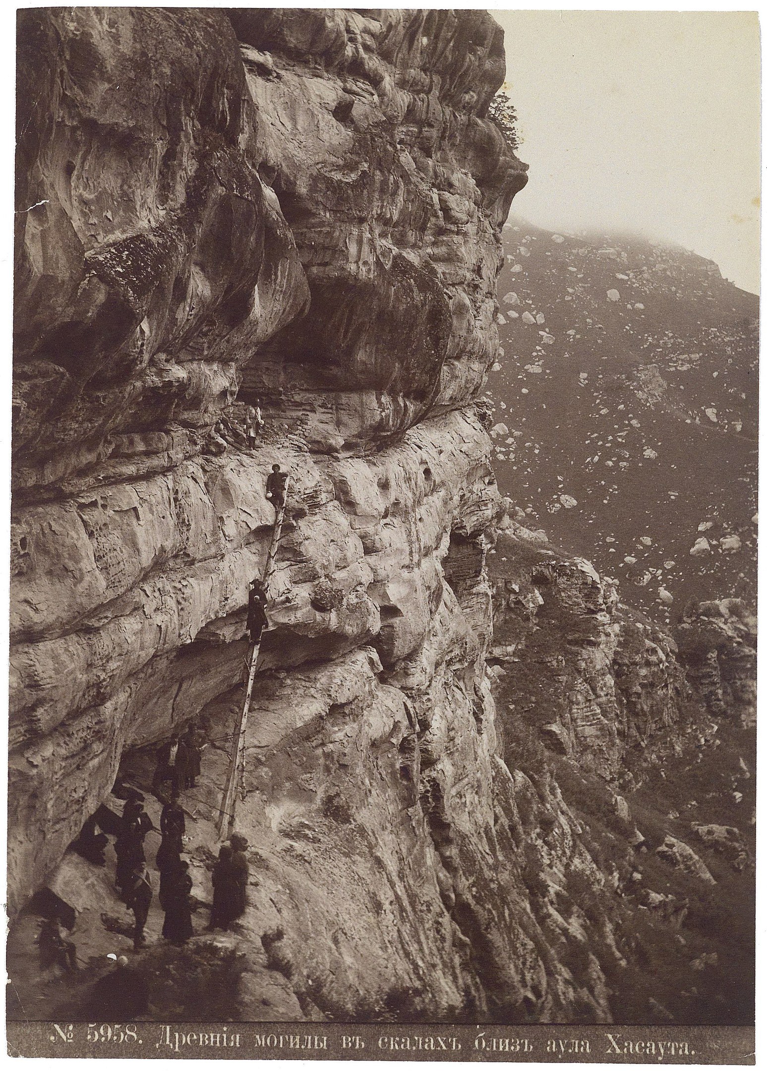 Schwarz-weiß-Foto von Menschen, die eine Klippe hochklettern, mit Text unten.
