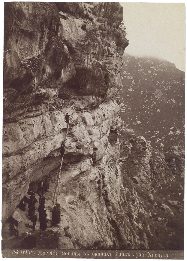 Schwarz-weiß-Foto von Menschen, die eine Klippe hochklettern, mit Text unten.