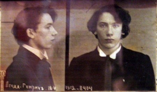 Ein Fahndungsfoto eines Mannes in einem schwarzen Anzug, weißem Hemd und schwarzer Krawatte mit ernstem Gesichtsausdruck, geführten Händen und zurückgekämmten Haaren, begleitet von zwei weiteren Fotos und fetter Textbeschreibung seiner Verbrechen.