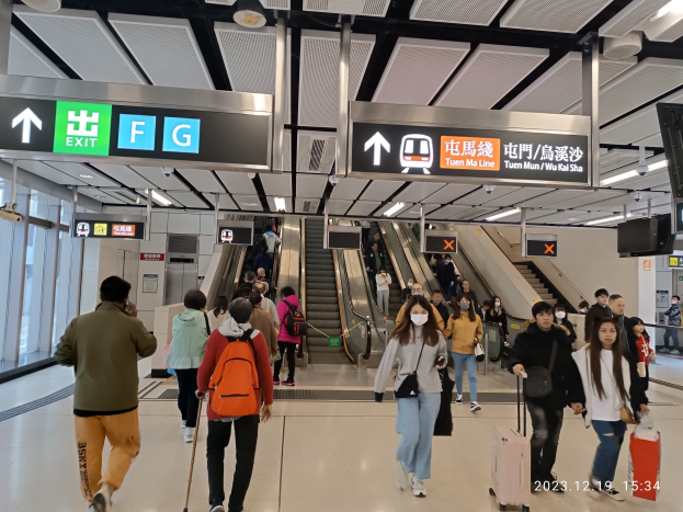 Eine Gruppe von Menschen mit Gepäck geht durch einen Flughafen mit Rolltreppen, Textanzeigen, Deckenlampen und Glaswänden im Hintergrund, mit einem Wasserzeichen, das den Flughafen aufgrund der Coronavirus-Pandemie als geschlossen kennzeichnet.