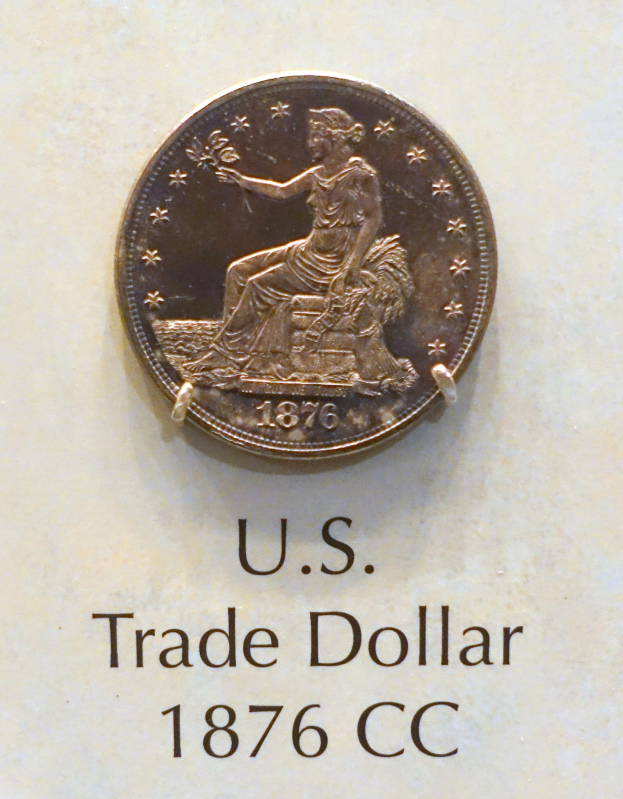 Ein US-Handelsdollar-Münze aus dem Jahr 1876, markiert mit "CC", mit auffälliger schwarzer Schrift auf einer polierten Silberoberfläche.