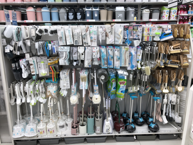 Ein Regal mit verschiedenen Reinigungsutensilien wie Bürsten, Flaschen und Tassen mit Preisschildern, das sich in den Philippinen befindet.