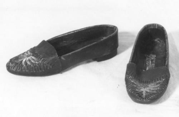 Schwarze Lederschuhe mit glänzender Oberfläche, gerundeter Spitze und niedrigem Absatz auf einer weißen Oberfläche, mit einer strukturierten Sohle für besseren Halt.