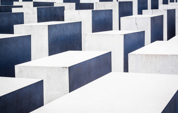 Ein Feld aus Betonplatten verschiedener Höhen, die in einem Gittermuster angeordnet sind, bekannt als Holocaust-Mahnmal für die ermordeten Juden Europas in Berlin, Deutschland.
