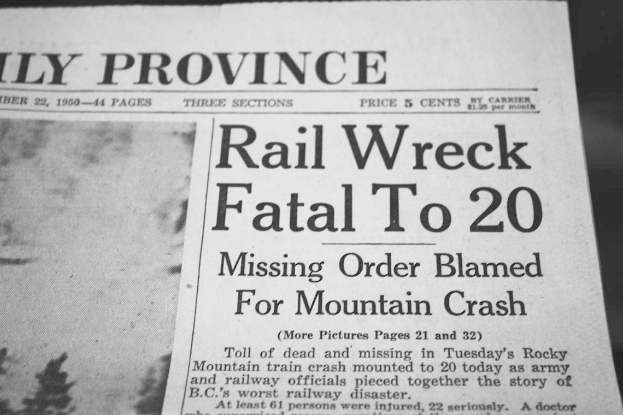Schwarze und weiße Zeitung mit der Schlagzeile "Rail Wreck Fatal to 20" und einem Hintergrundbild von einem Zugunglück.