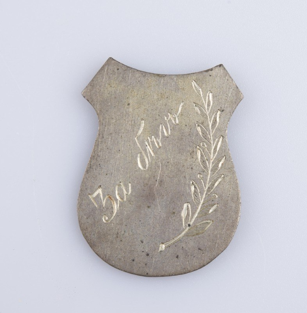 Ein silbergerändertes Abzeichen mit einem Lorbeerkranz, der die Inschrift "50-jähriges Jubiläum" trägt.