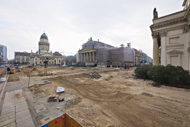 Großbaustelle mit Berliner Dom im Hintergrund, Bäumen rechts, Fahrzeugen links und Himmel oben.