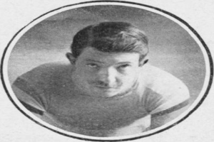 Schwarzes und weißes Foto eines Mannes in einem Football-Outfit mit ernster Miene, der eine Football-Jersey und kurze dunkle Haare trägt.