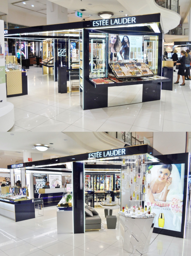 Estee Lauder Kosmetikgeschäft in einem Einkaufszentrum mit Menschen, die die angezeigten Artikel betrachten, helles Licht und einer Fotocollage an den Wänden.