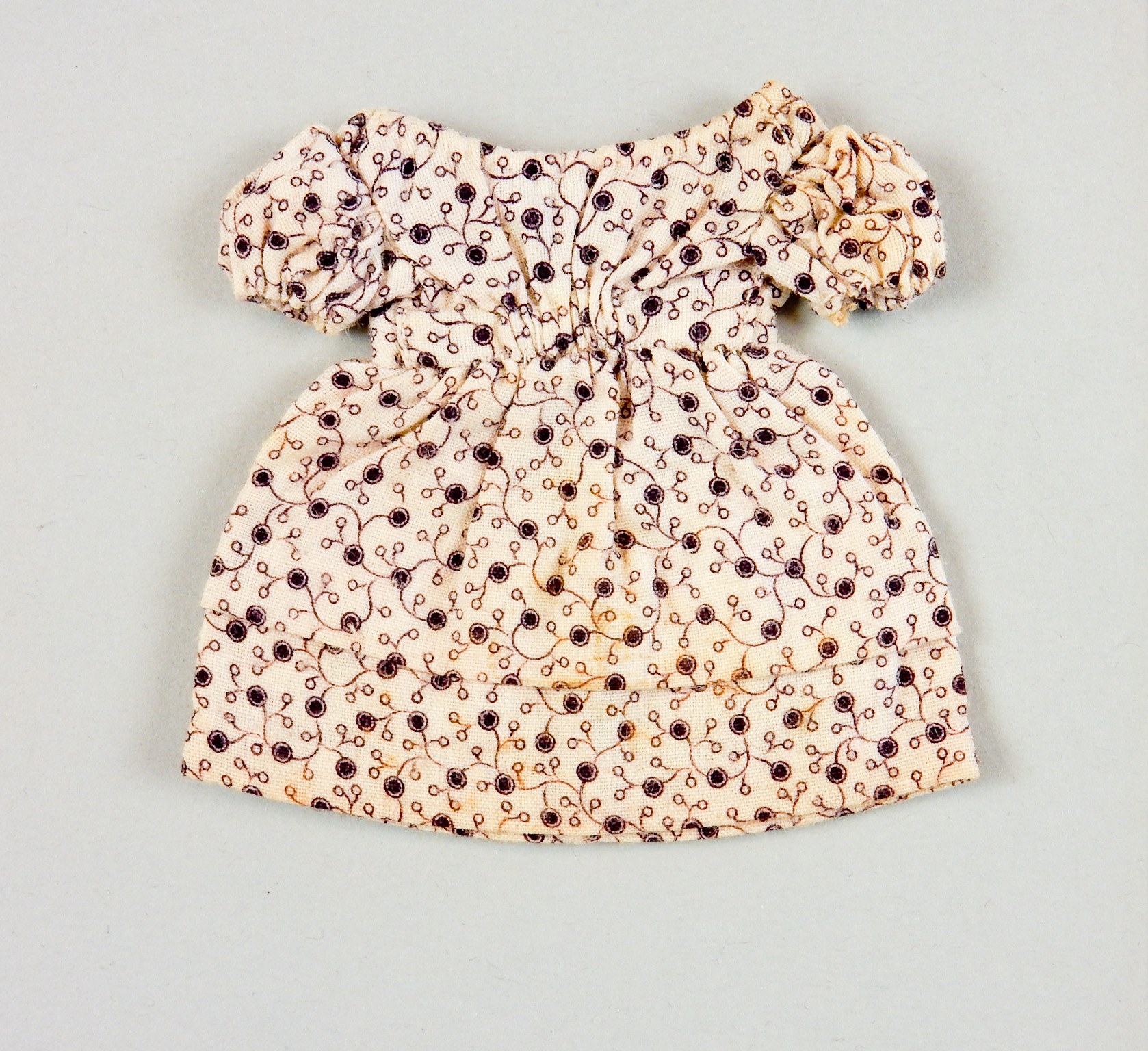 Ein weißes Sommerkleid mit rundem Halsausschnitt, kurzen Ärmeln und einem Volantsaum, das ein komplexes mehrfarbiges Muster aufweist, auf einer weißen Oberfläche präsentiert.