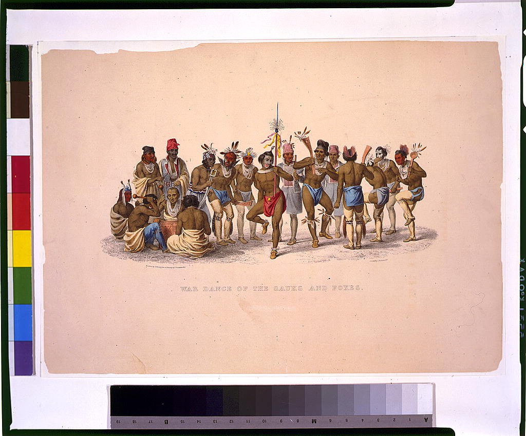 Gruppe von Männern in traditioneller indianischer Kleidung führt einen Kriegstanz auf einem farbenfroh bedruckten Papier mit sichtbarem Text aus.