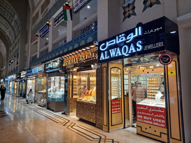 Ein belebter Einkaufszentrum in Dubai, UAE, mit Menschen, Geschäften, Namensschildern, Lichtern, Flaggen und einer Vielfalt an Schmuck.
