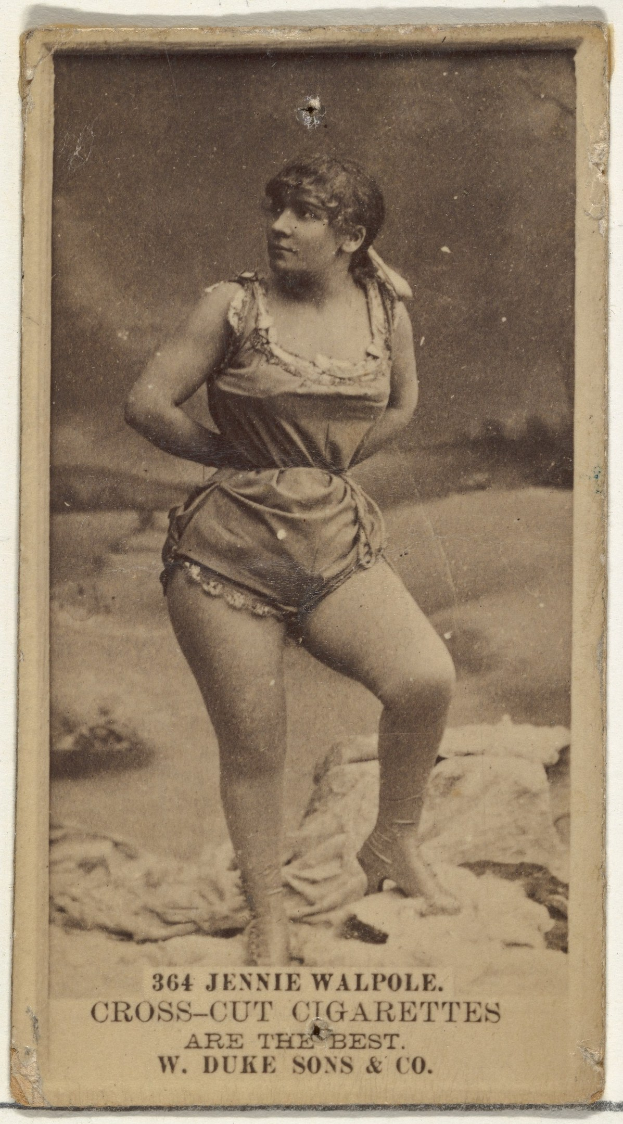 Ein Schwarz-Weiß-Foto einer älteren Frau in einem vintage-Badeanzug, die selbstbewusst am Strand steht, mit geschlossenen Augen und leicht geöffneten Lippen, mit Text unten.