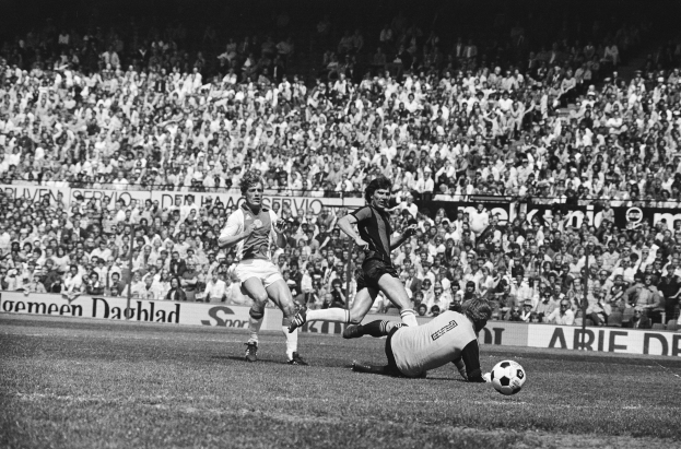 Schwarzes Foto von Fußballspielern im Einsatz auf einem Feld mit Zuschauern im Hintergrund und einer Bundesliga 1978-79 Ajax 1-1 Hannover 96-Banner.