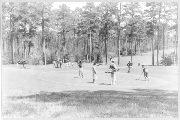 Schwarzes und weißes Bild von Menschen, die Golf auf einem baumbewachsenen Kurs spielen, mit Text unten.