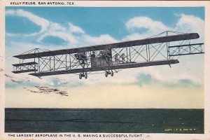 Ein altes Foto des größten US-Flugzeugs bei einem Flug mit sichtbaren Passagieren und Wolken am Himmel, mit Text am unteren Bildrand.