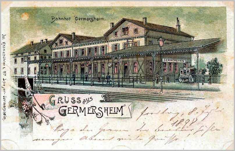 Schwarz-weiß-Postkarte vom Bahnhof Germersheim in Deutschland, die ein Bahnhofsgebäude, Menschen, Fahrzeuge, Bäume und einen bewölkten Himmel zeigt.
