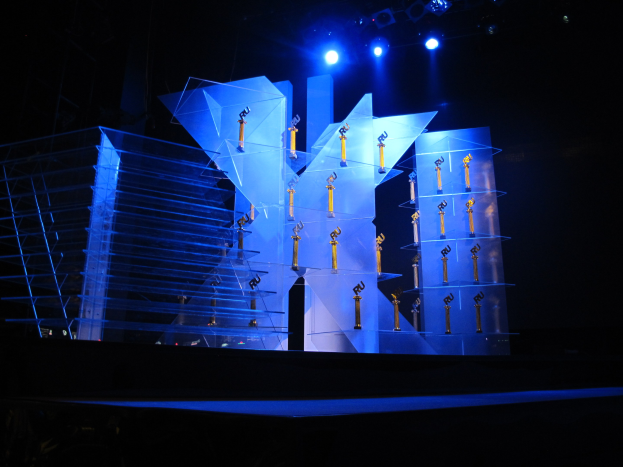 Eine Bühne für eine Preisverleihung mit dunklem Hintergrund, ein paar Lichtern und einigen Gegenständen, die mit dem Ereignis in Verbindung stehen.