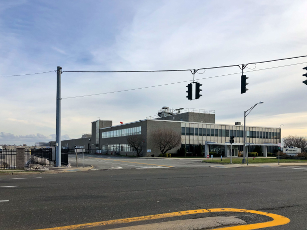 Large building with numerous traffic lights, street poles, and electric infrastructure, surrounded by motor vehicles, trees, and a cloudy sky, identified as the National Security Agency's new headquarters.