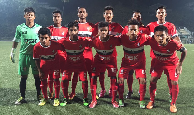 Spieler der Bangladesh-Nationalmannschaft für Fußball auf einem hell erleuchteten Führboden bei Nacht, mit einem vollen Stadion im Hintergrund.