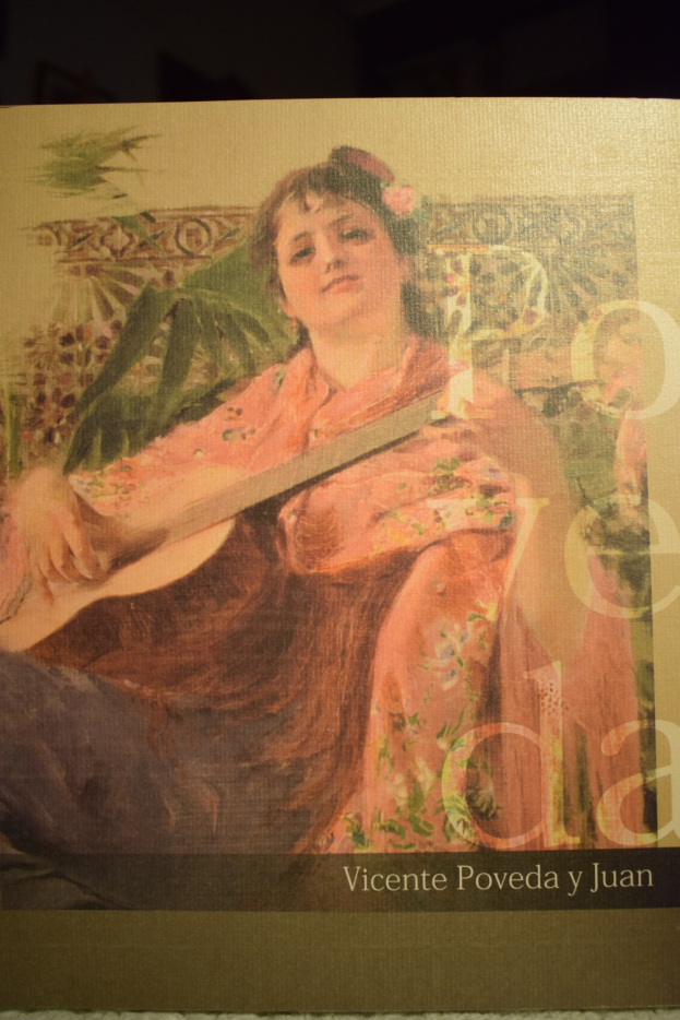 Eine Frau mit einem Dutt sitzt auf einem Sofa, hält eine Gitarre und hat die Augen geschlossen, trägt ein weißes Kleid und einen gemusterten Schal, vor einem hellblauen Hintergrund mit der Aufschrift "Vicente Poveda y Juan".