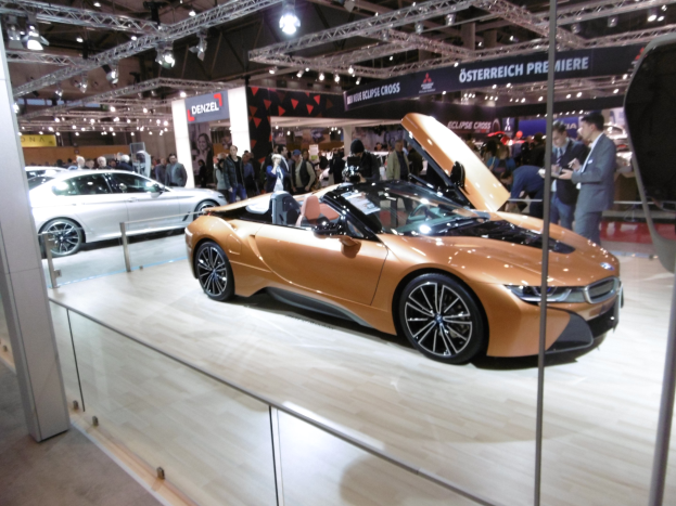 Schwarzer BMW i8 Roadster mit glänzender Lackierung und Chromakzenten, präsentiert auf der IAA in Frankfurt, umgeben von formell gekleideten Gästen.