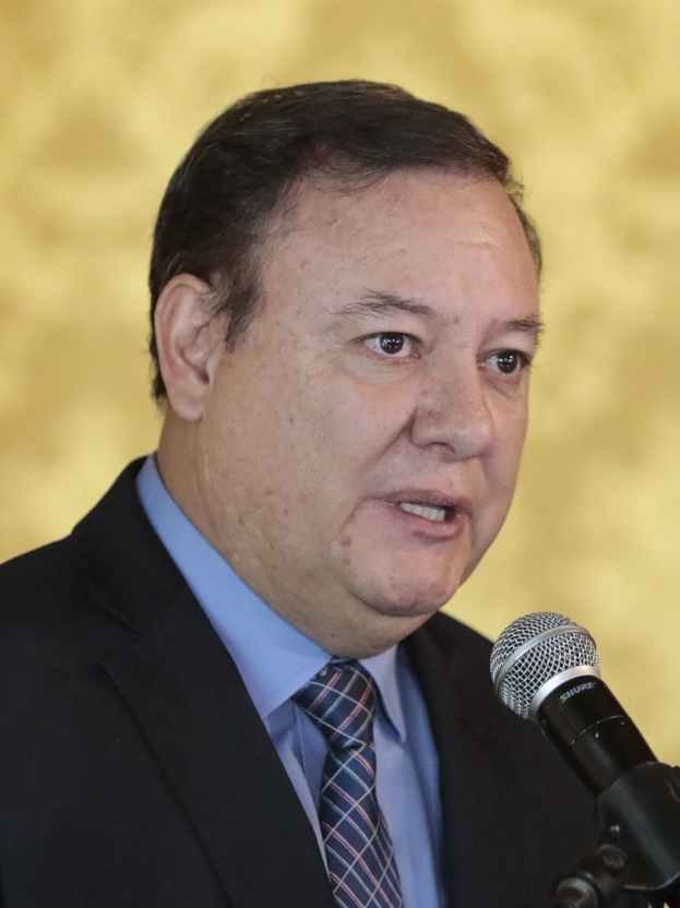 Ein Mann im Anzug und mit Krawatte, der als Generalstaatsanwalt identifiziert wurde, spricht in ein Mikrofon mit einem unscharfen Hintergrund.