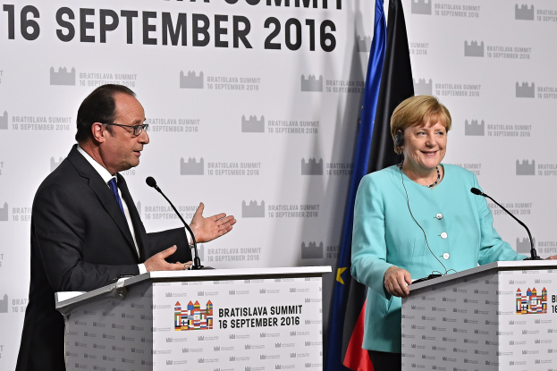Bundeskanzlerin Angela Merkel und Frankreichs Präsident François Hollande lachen auf Podien während des Bratislava-Gipfels 2016, mit einem Banner im Hintergrund, auf dem 'Bratislava-Gipfel 2016' steht.