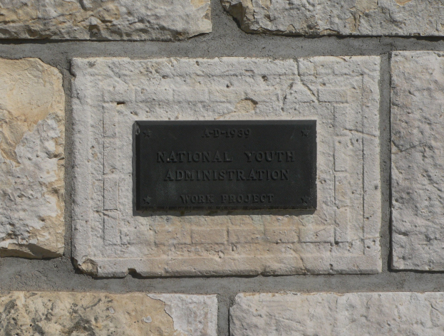Steinwand mit einem rechteckigen Schild, auf dem in fetten weißen Buchstaben "Nationales Jugendamt" steht.