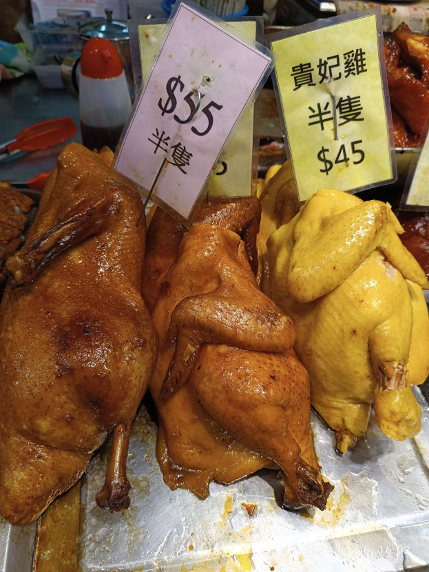 Eine Gruppe von Hühnern auf einem Metalltablett mit Preisschildern in einem Markt.