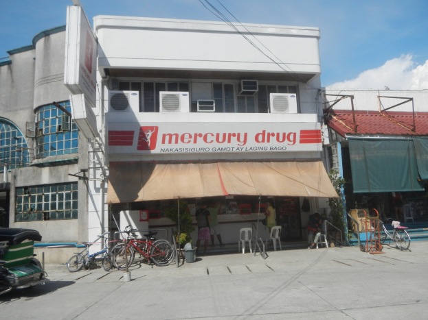 Außenansicht eines Mercury-Drug-Ladens in den Philippinen mit Gebäuden, Fahrzeugen, Fahrrädern, Fußgängern und städtischen Elementen wie Klimaanlagen und Strommasten.