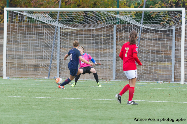 Gruppe von Frauen, die auf einem Rasenfußballfeld mit Bäumen im Hintergrund und einem Torpfosten spielen, mit Text unten.