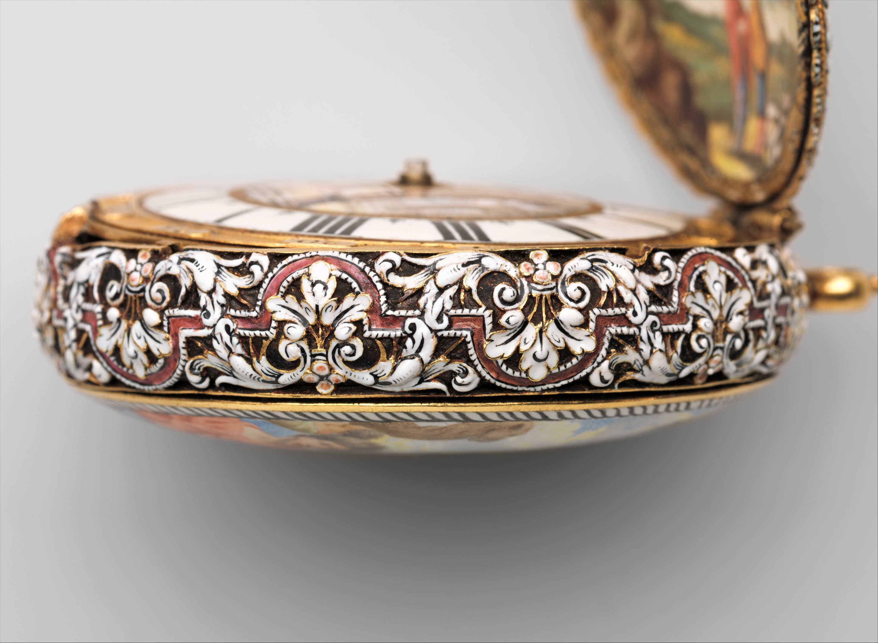 Close-up of a pocket watch with a painted face, featuring intricate encrusted designs and an elegant, luxurious appearance.