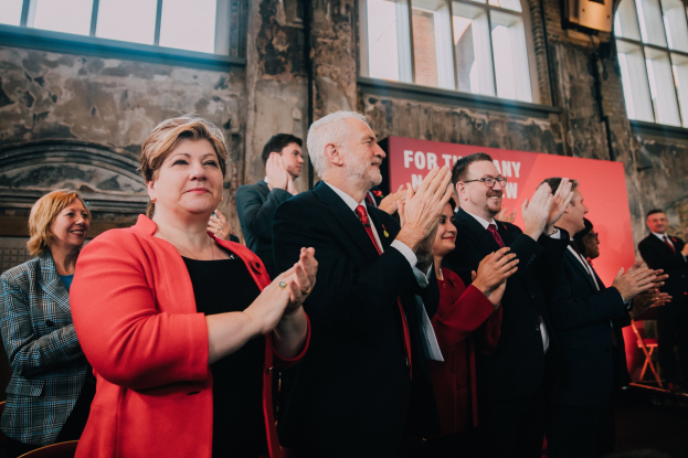 Menschen klatschen feierlich vor einer Menge mit einem Wahlsieg-Banner im Hintergrund.